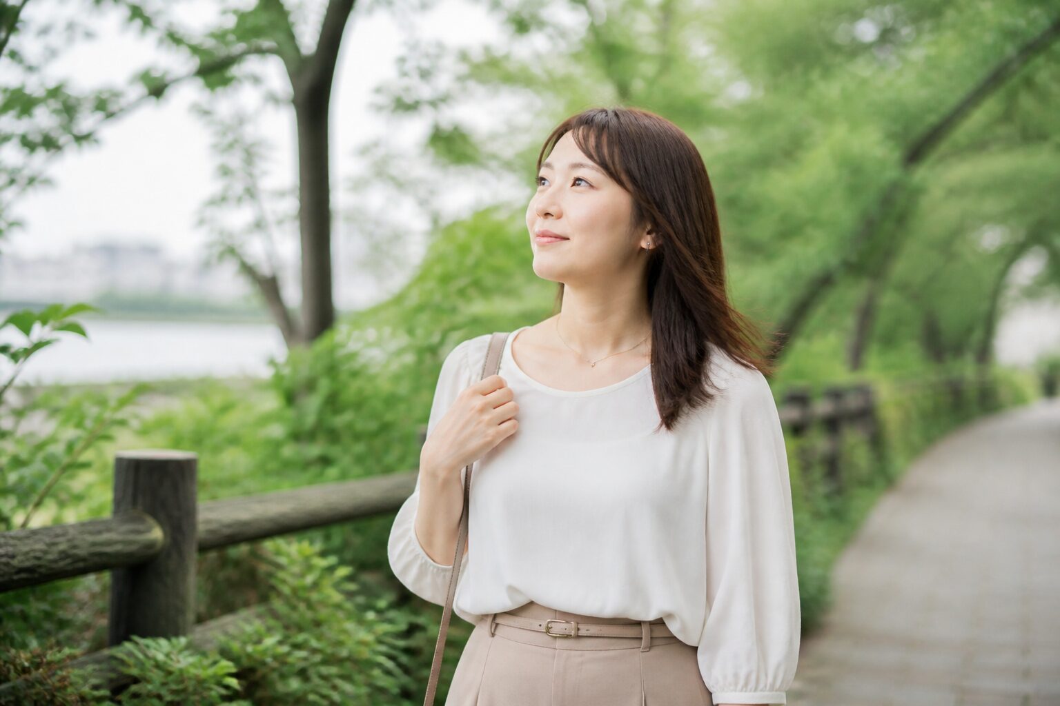 緑のある道をゆっくり歩き気持ちを整える女性