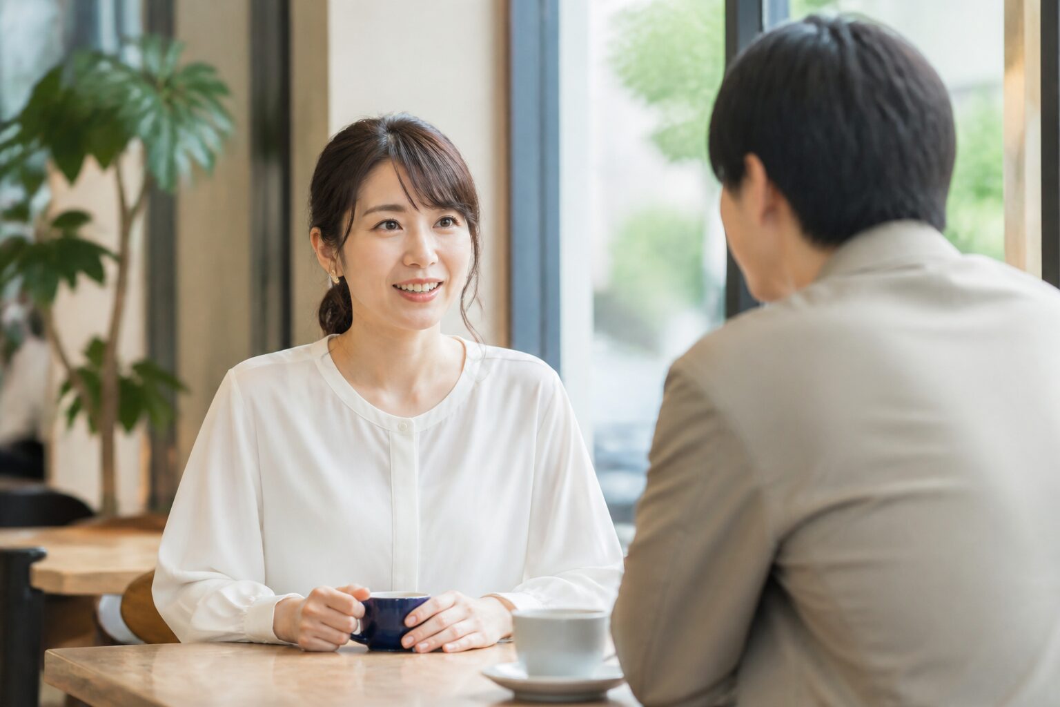 明るいカフェで相手と穏やかに会話する30代女性