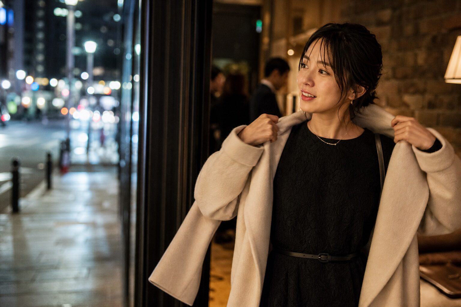 忘年会を終えて店の入口でコートを着る女性
