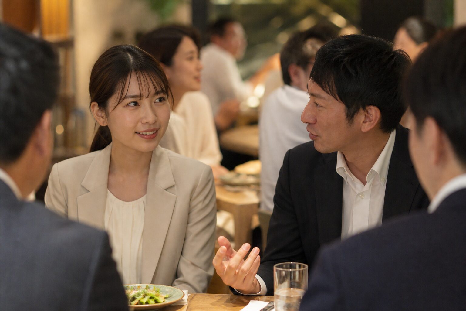 忘年会の席で自然に会話する男女
