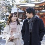 冬の神社の近くを歩く男女