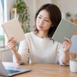 二冊のノートを比べて考える女性