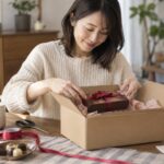 自宅で贈り物を発送用の箱に入れる女性