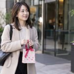 職場の外で小さなギフト袋を持つ女性
